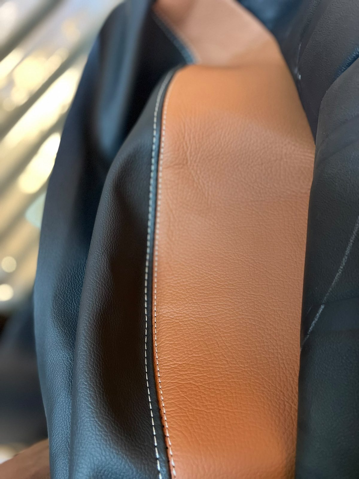 Contrast white stitching between tan and black leather panels